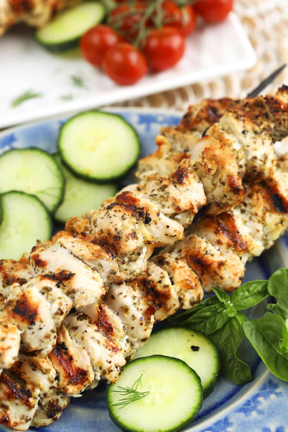 Chicken souvlaki skewers on platter with cucumbers