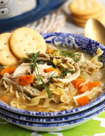 Bowl of crockpot chicken noodle soup with crackers