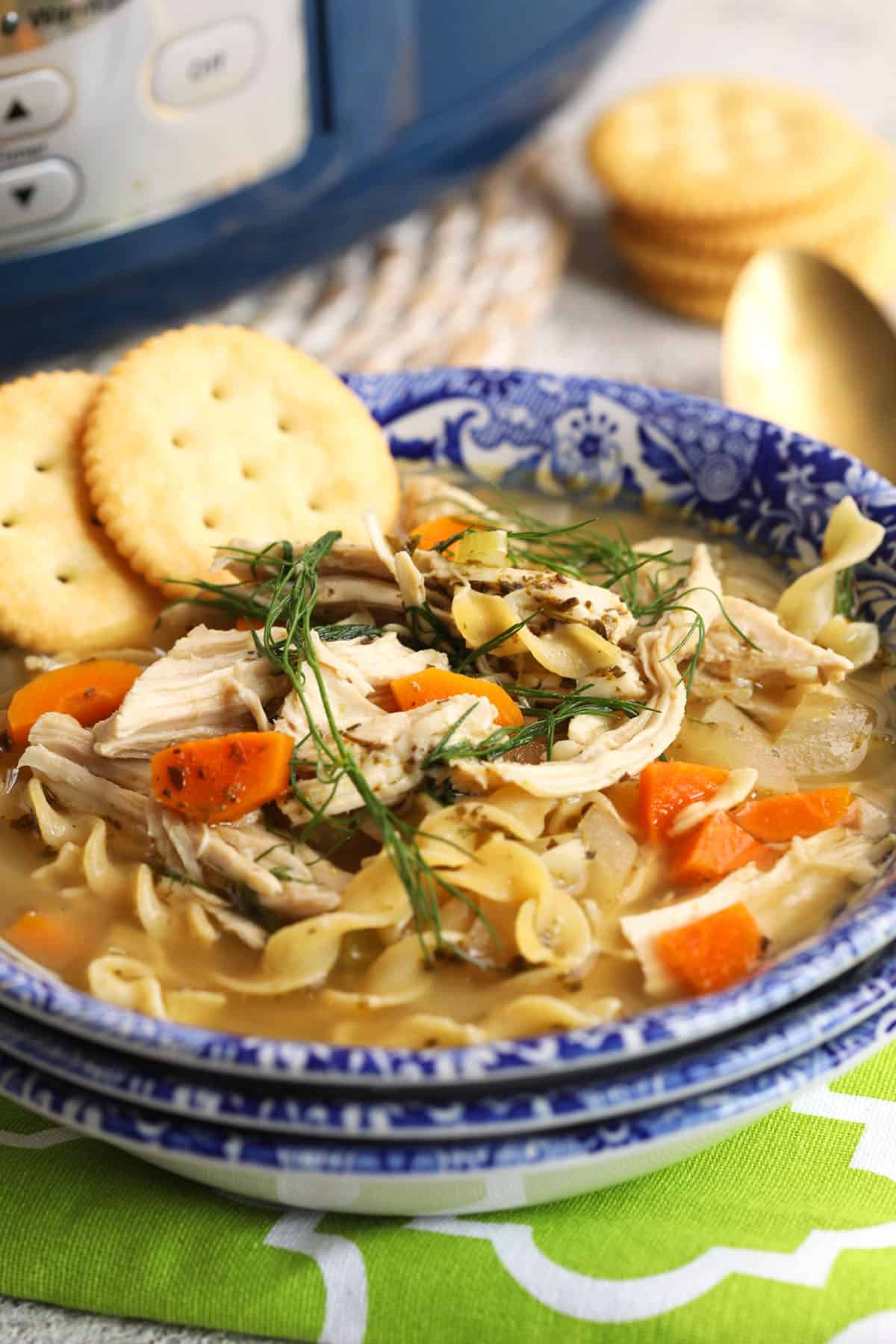 Bowl of crockpot chicken noodle soup with crackers