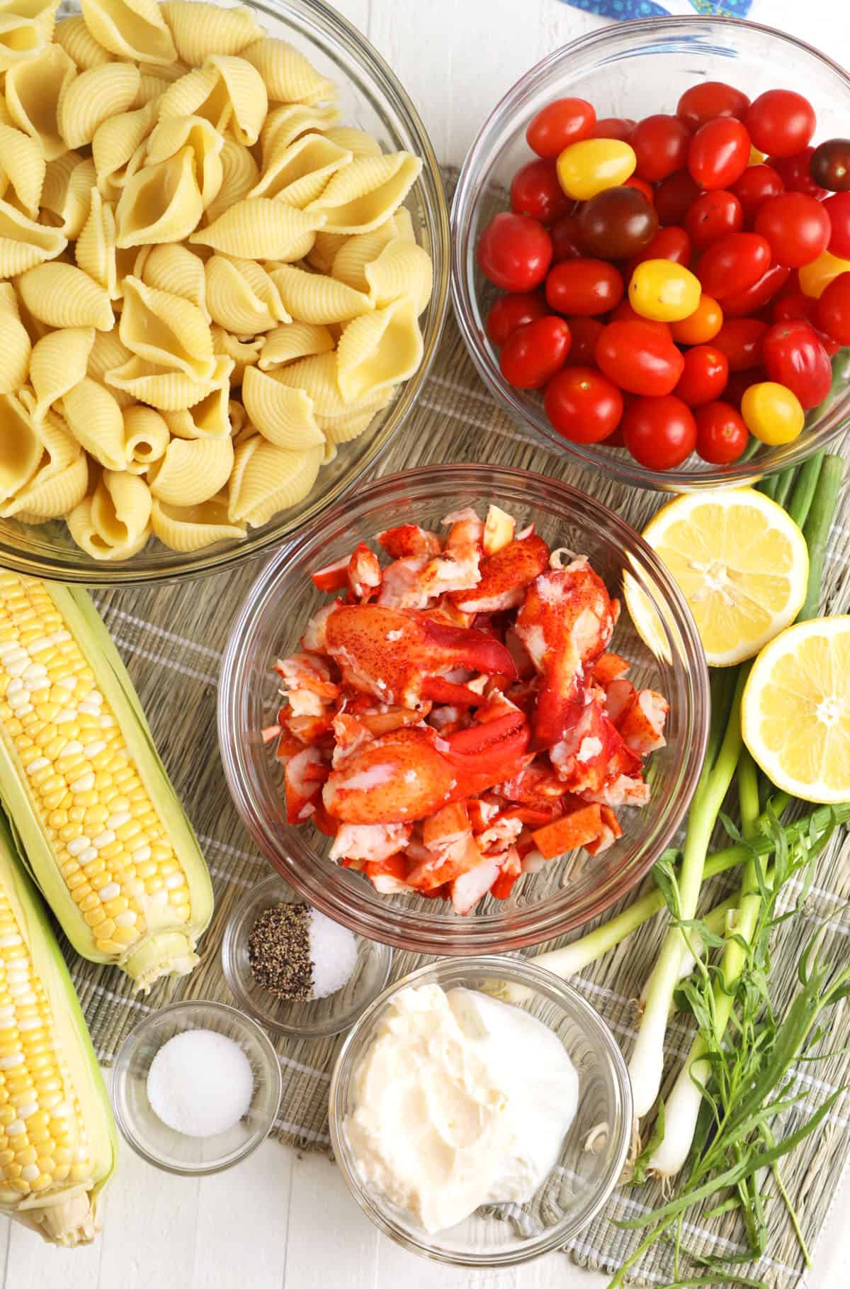 ingredients for lobster pasta salad on a seagrass background.