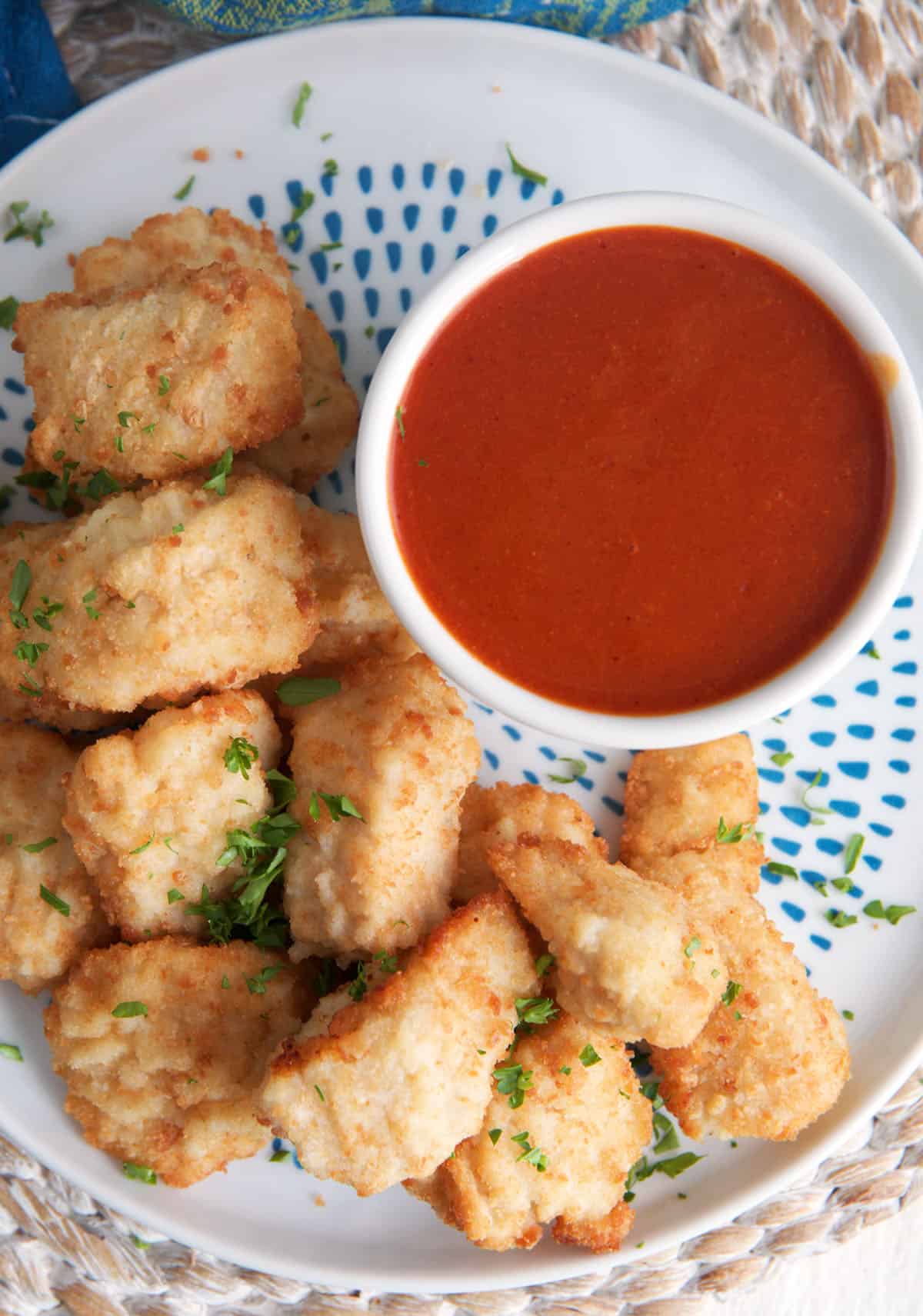 Overhead view of copycat Polynesian sauce in cup on plate of chicken nuggets