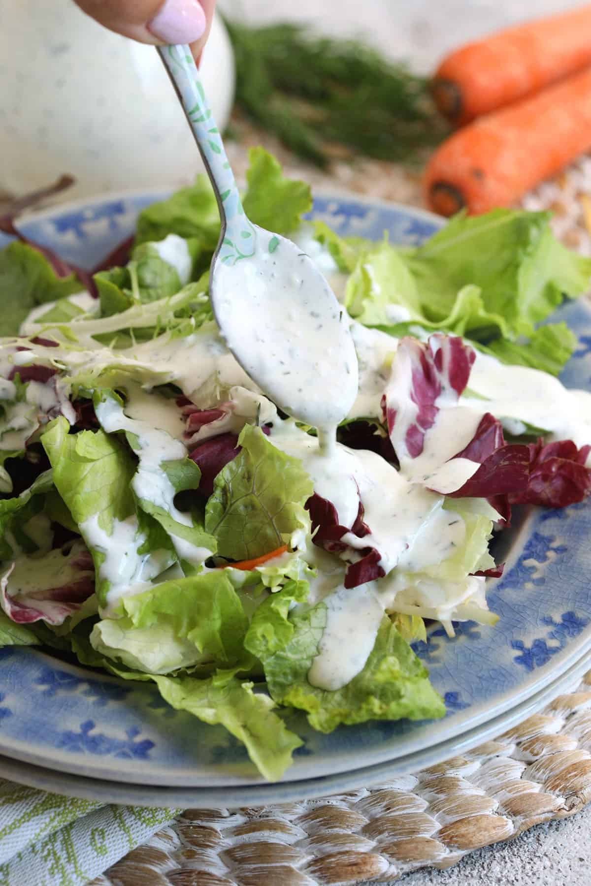 Drizzling homemade ranch dressing onto salad