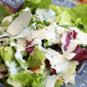 Drizzling ranch dressing onto salad