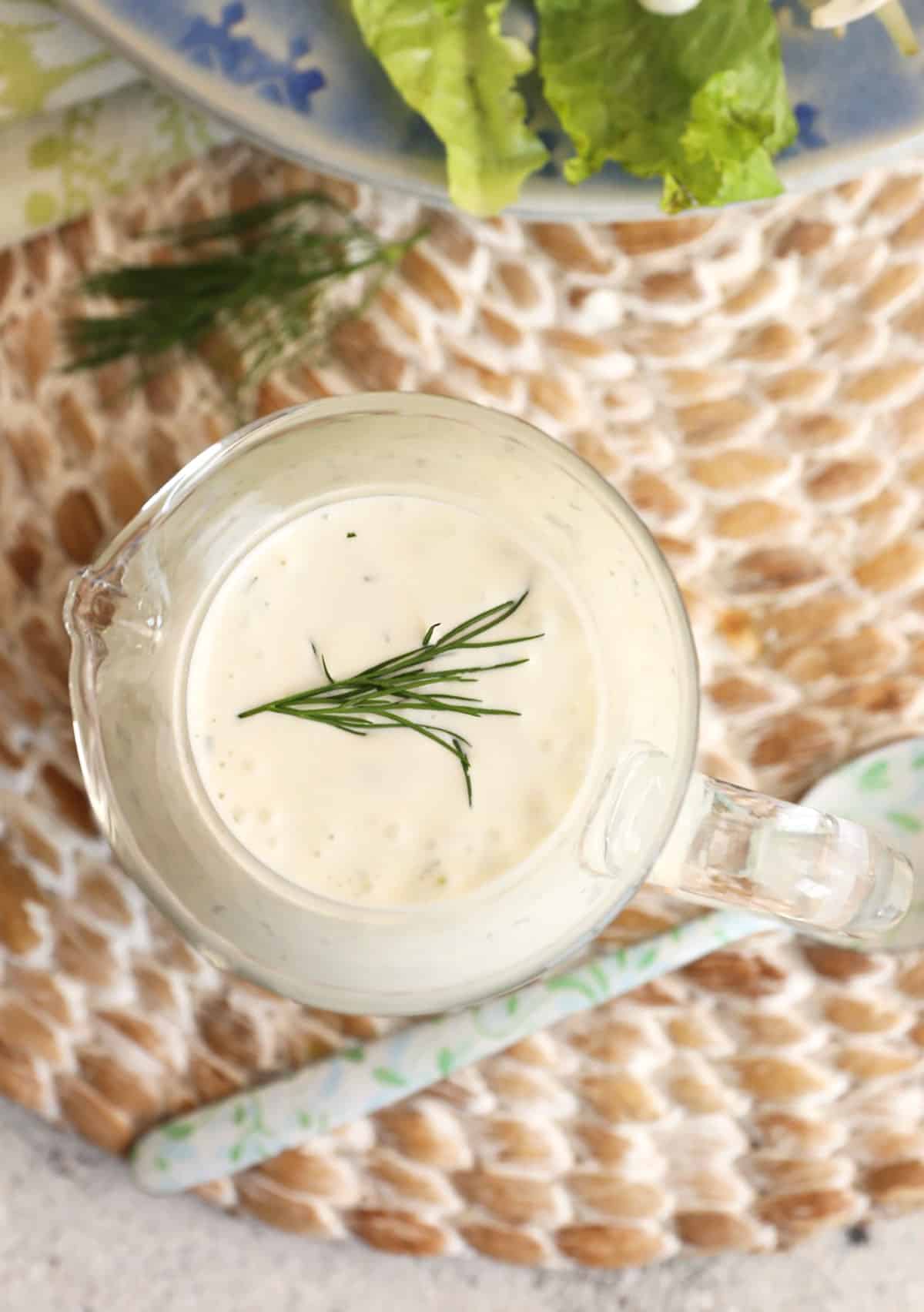 Ranch dressing in glass pitcher with dill on top