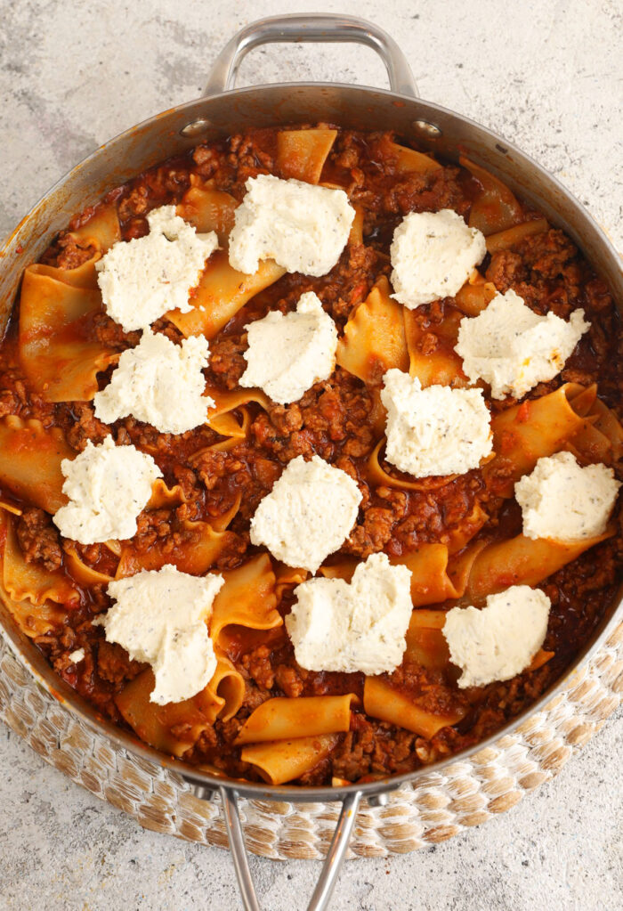 Ricotta cheese dolloped onto skillet lasagna