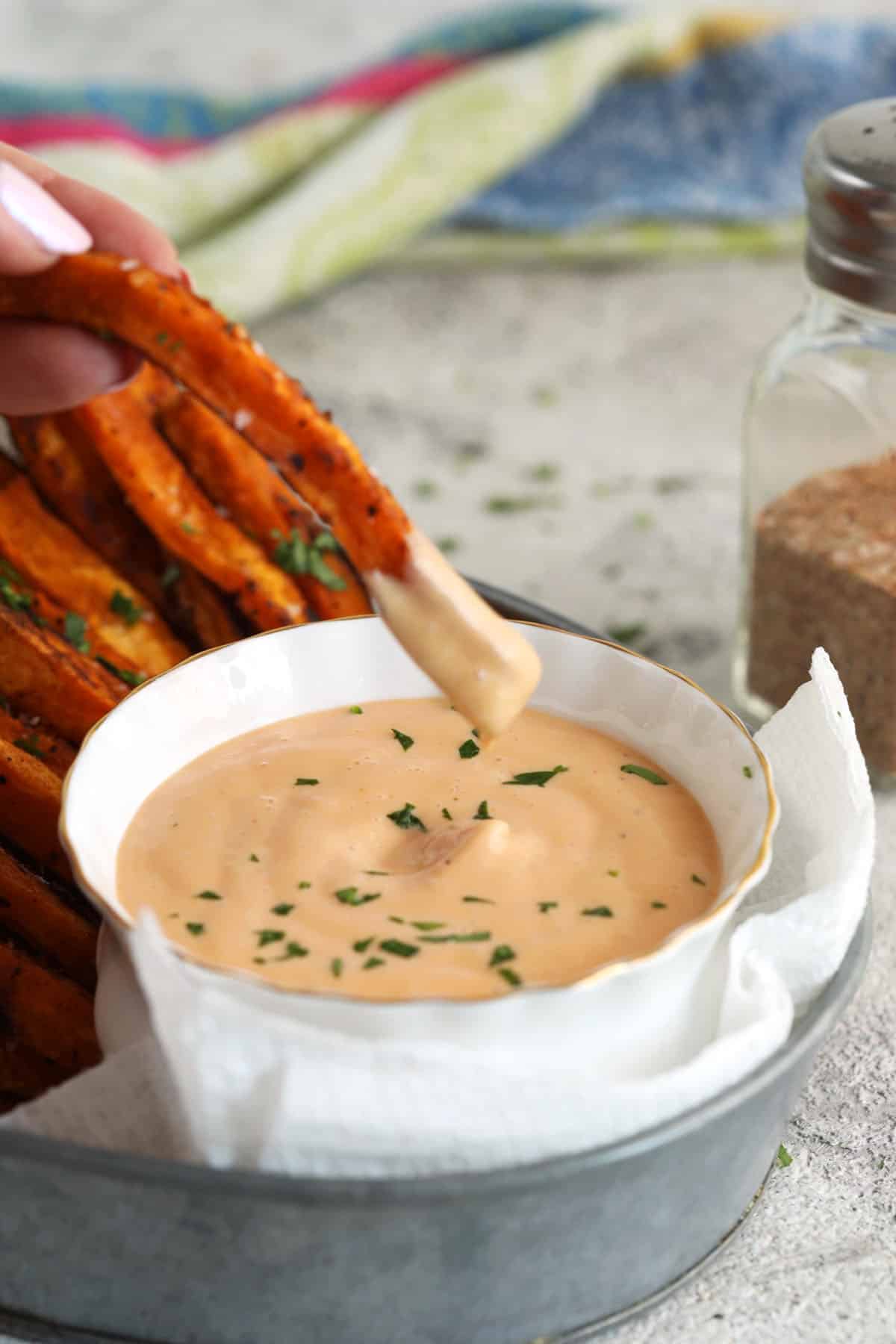 Dipping sweet potato fry into sauce