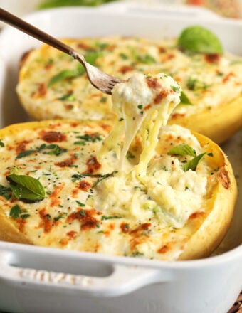 Pulling forkful of baked spaghetti squash alfredo from baking dish