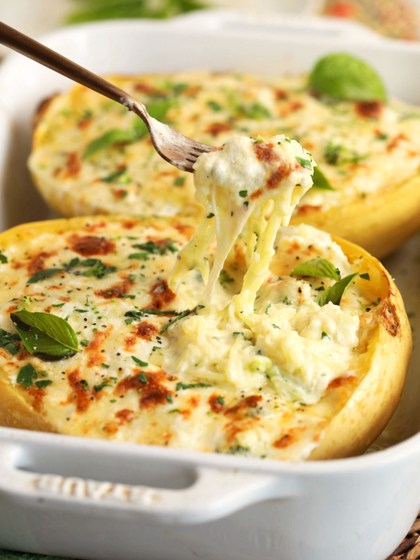 Pulling forkful of baked spaghetti squash alfredo from baking dish