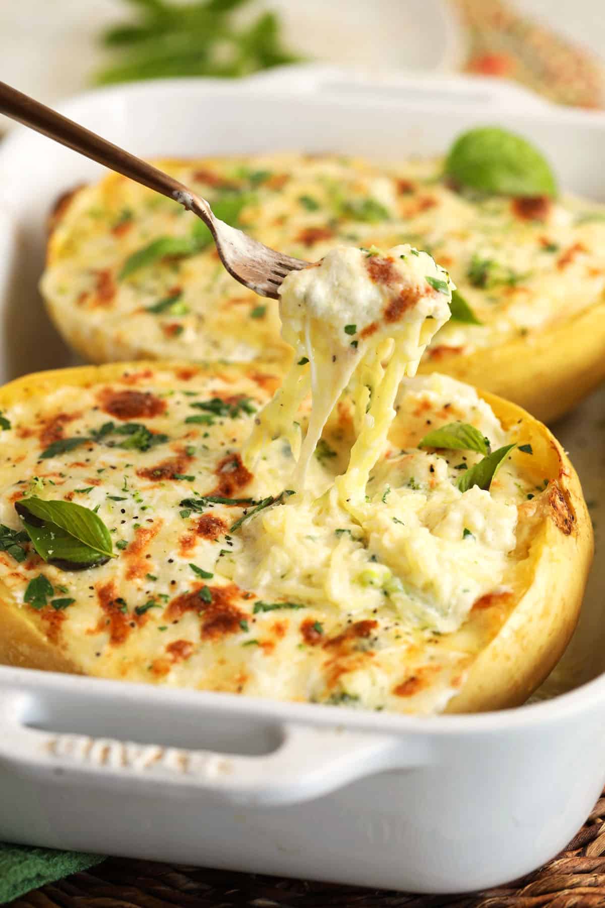 Pulling forkful of baked spaghetti squash alfredo from baking dish