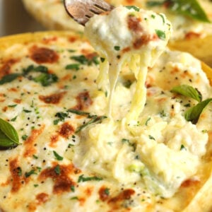 Fork pulling baked spaghetti squash alfredo from casserole dish