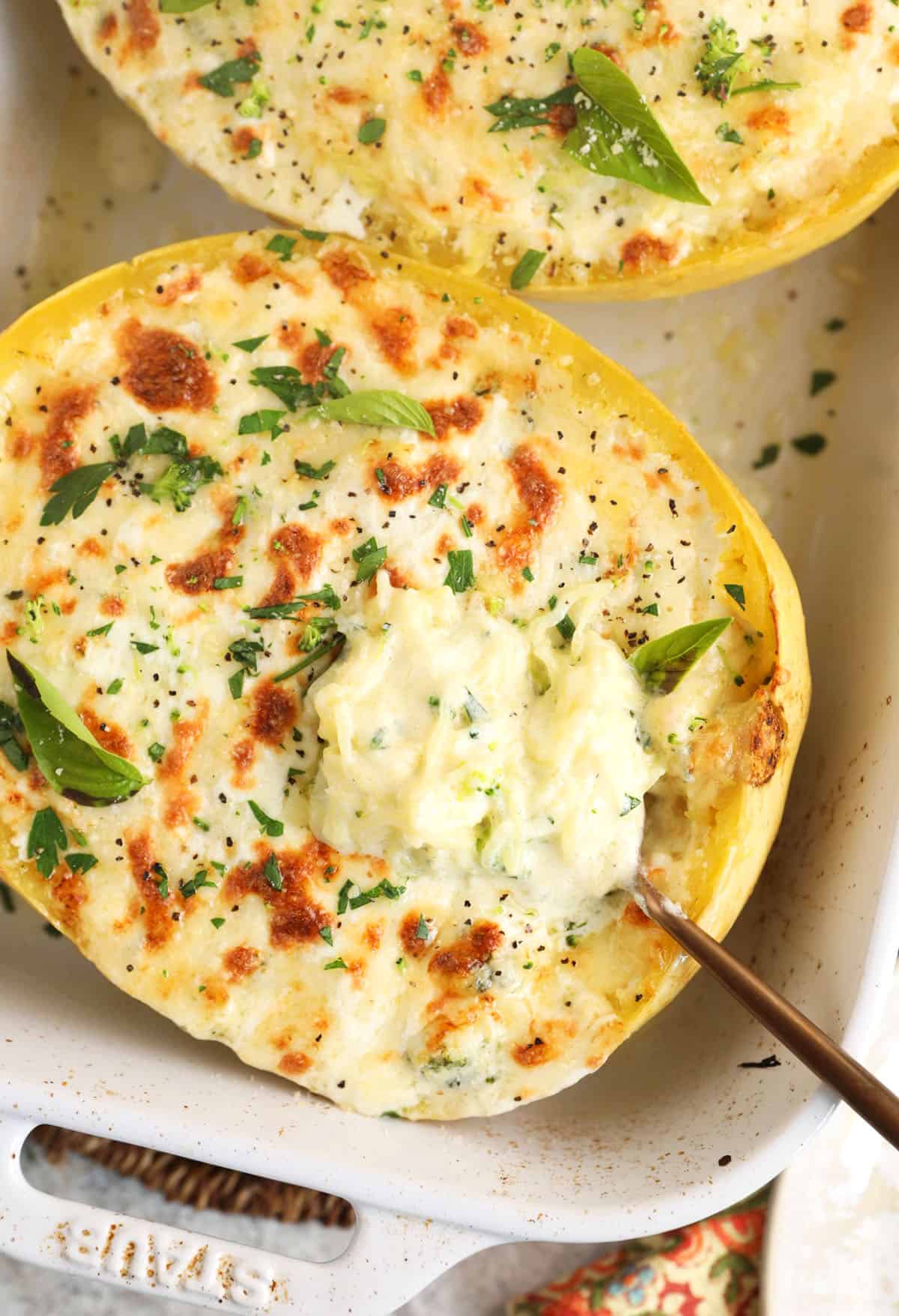 Forkful of creamy baked spaghetti squash alfredo held over baking dish