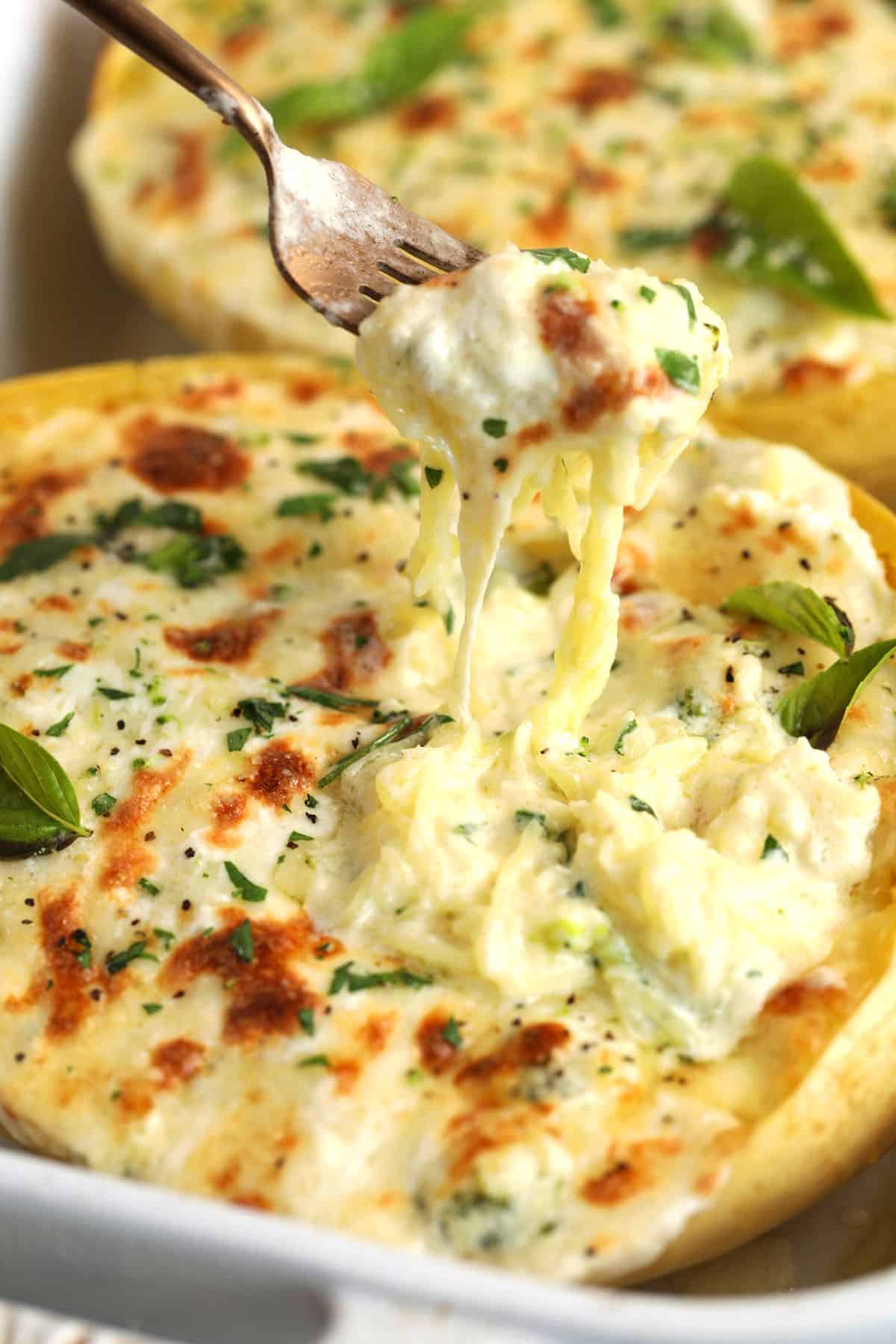 Fork pulling baked spaghetti squash alfredo from casserole dish