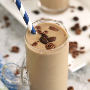 Creamy coffee smoothie in glass with straw