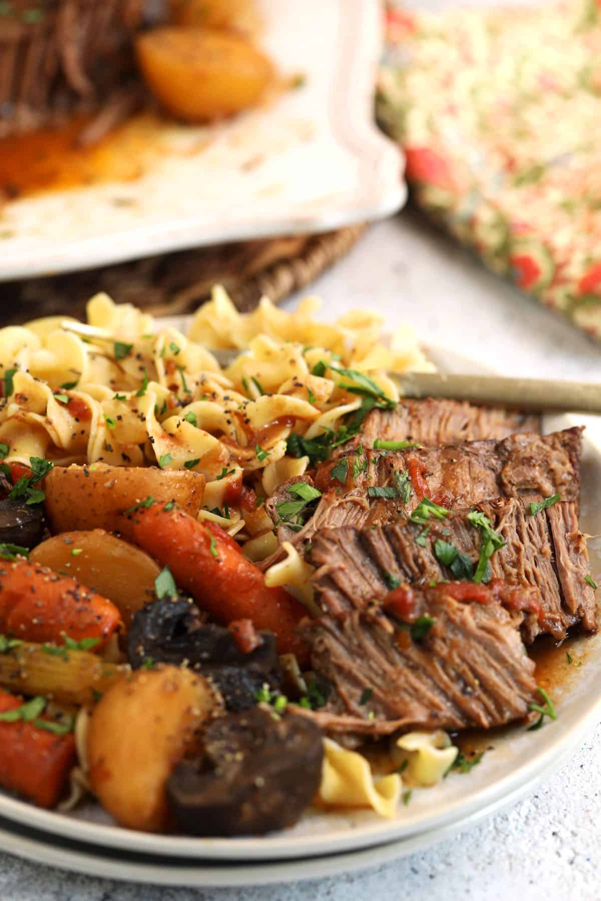 Plate of slow cooker pot roast, vegetables, and egg noodles