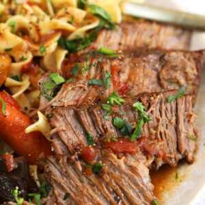 Crock pot pot roast on plate with egg noodles