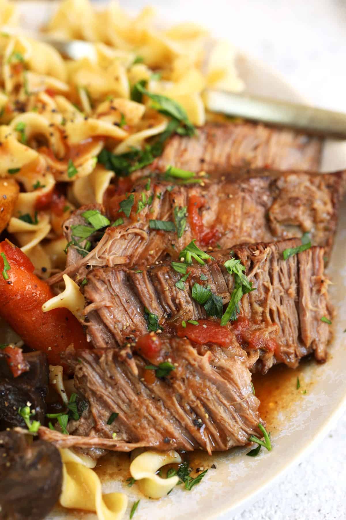 Crock pot pot roast on plate with egg noodles