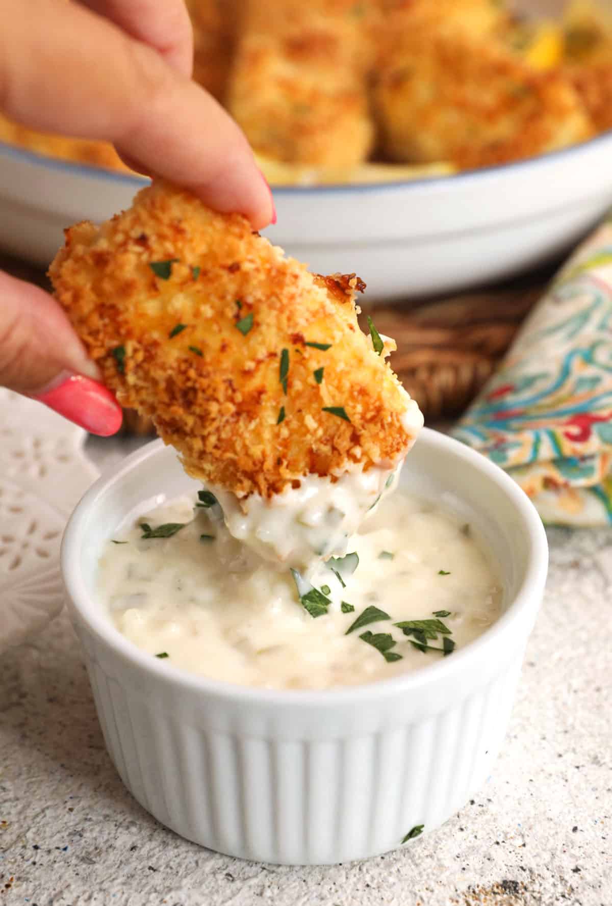 Dipping homemade fish stick in tartar sauce