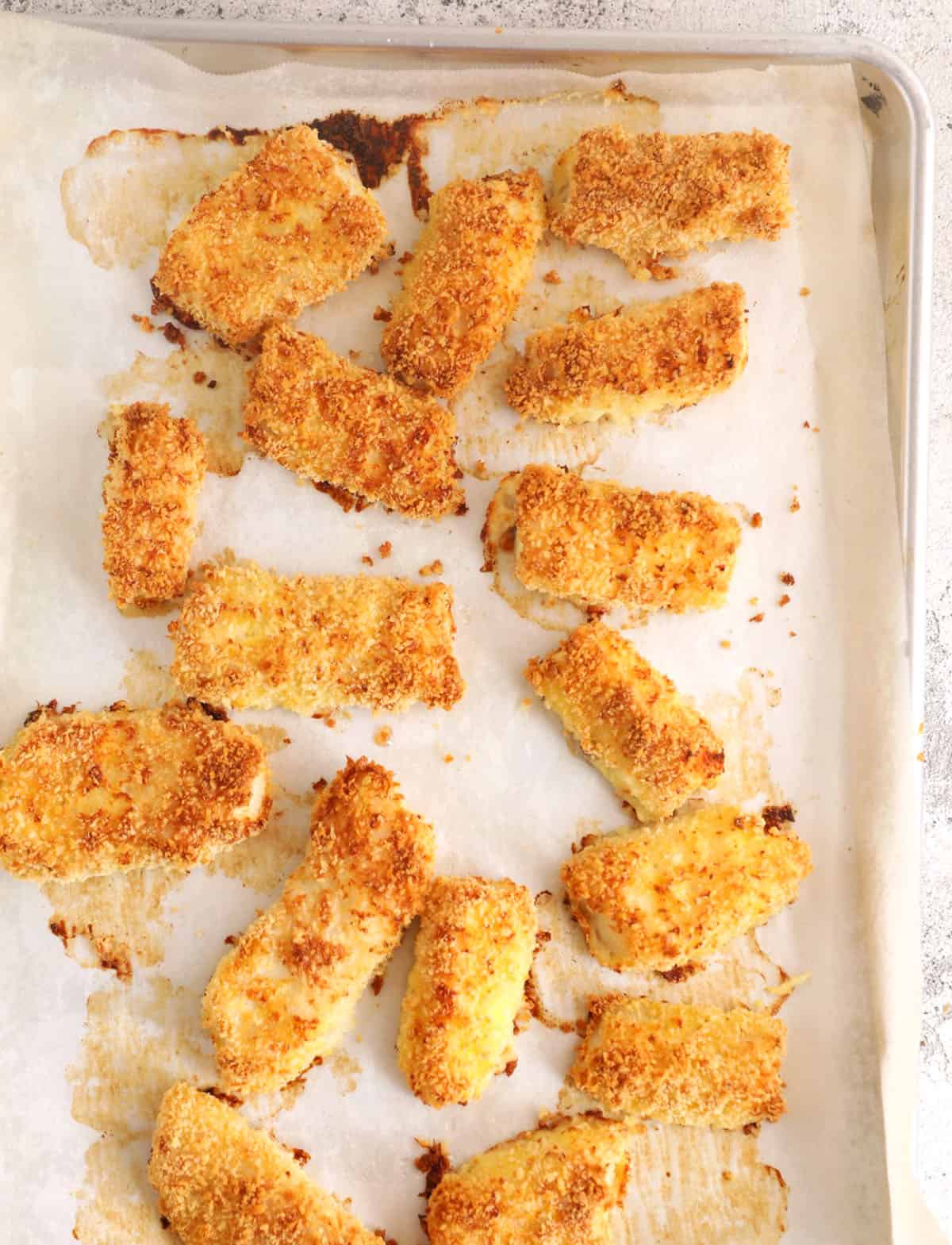 Overhead view of crispy homemade fish sticks on sheet pan