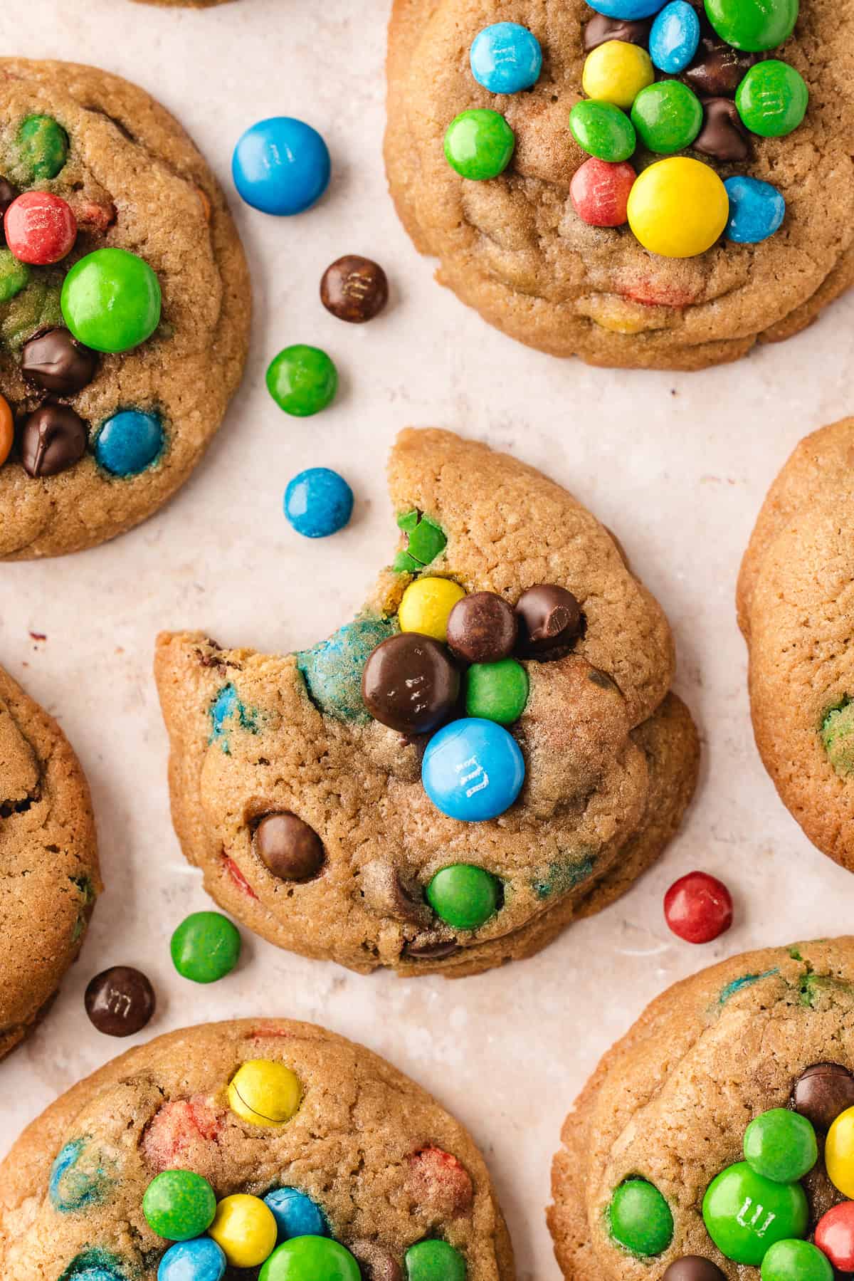 Overhead view of chocolate chip M&M cookies, with one in center bitten