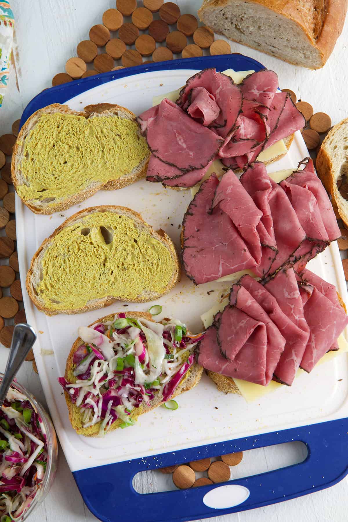 Overhead view showing assembly of pastrami sandwiches