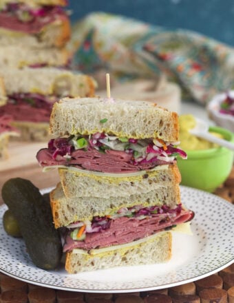 Two pastrami sandwich halves stacked on plate