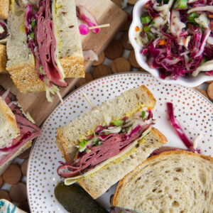 Overhead view of pastrami sandwiches on plate and cutting board