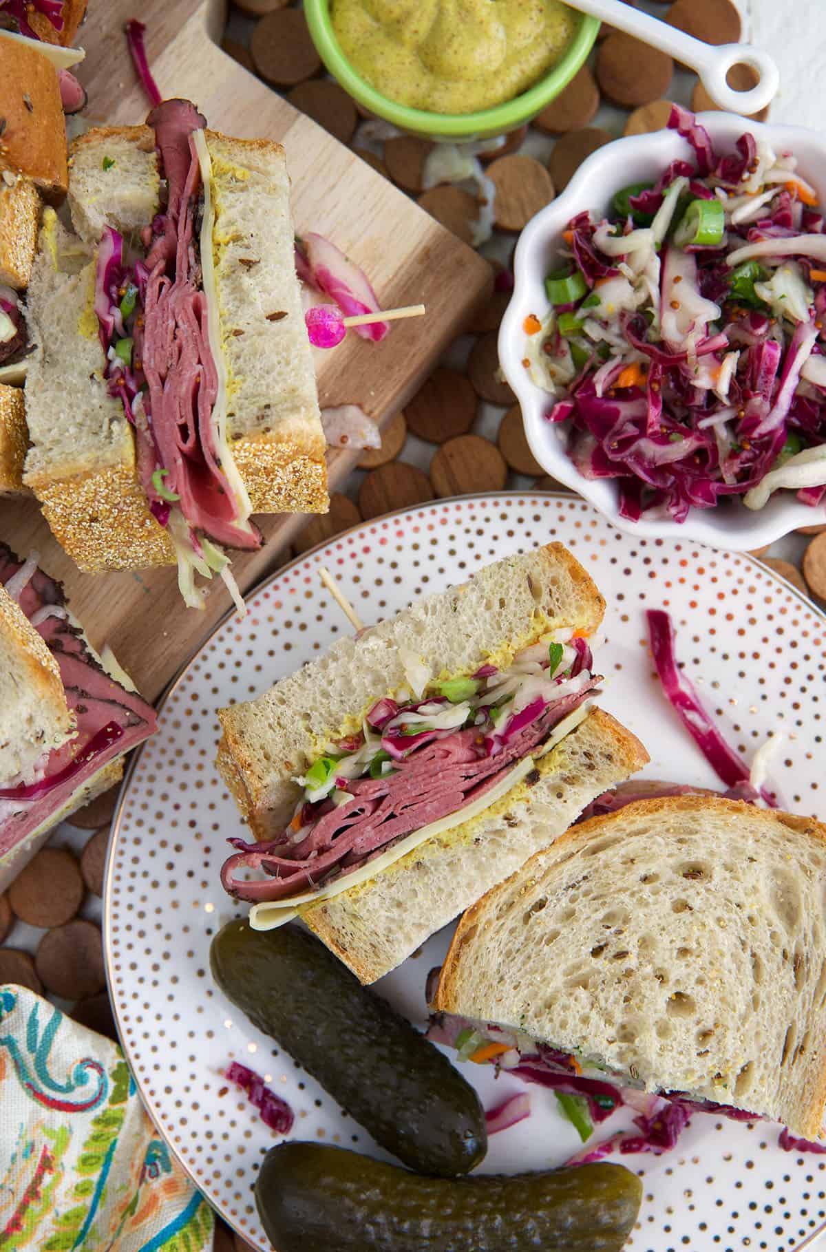 Overhead view of pastrami sandwiches on plate and cutting board