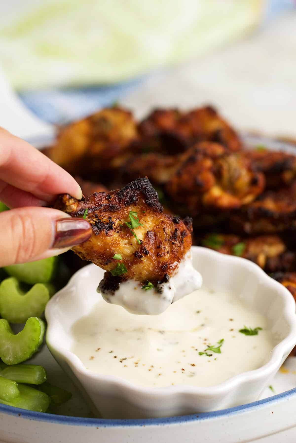 Dipping air fryer chicken wing into sauce