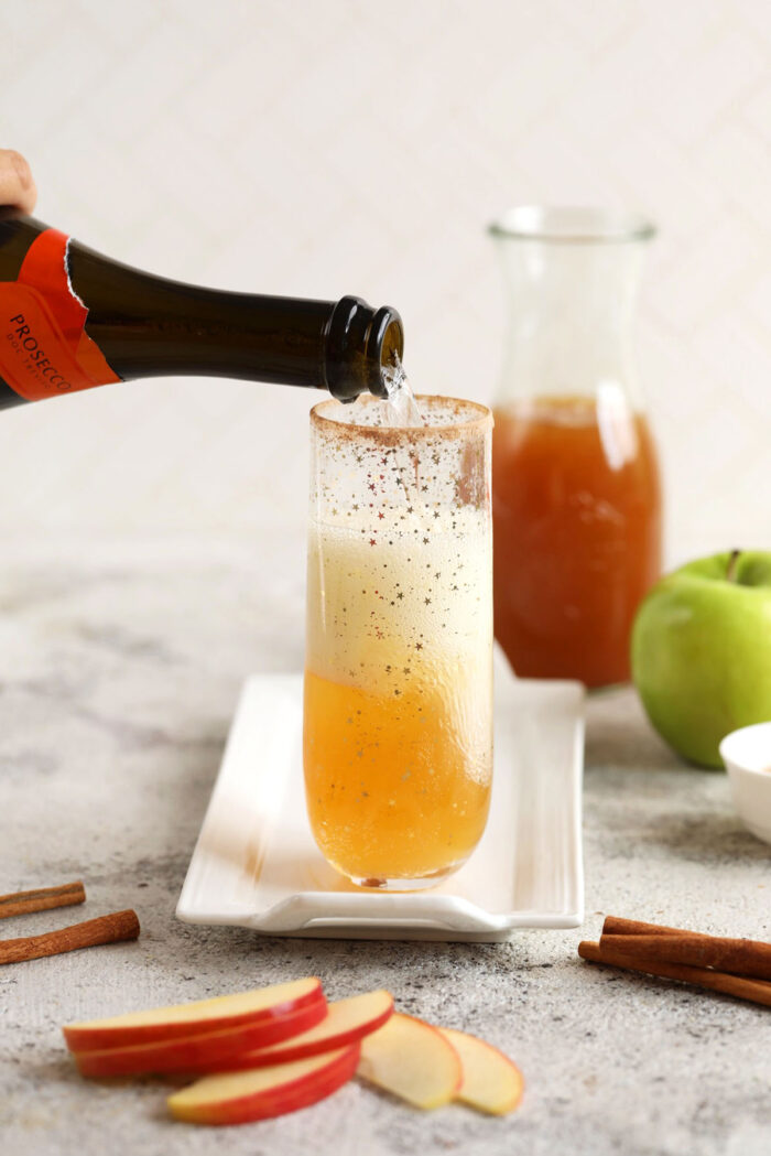 Pouring champagne into apple cider mimosa