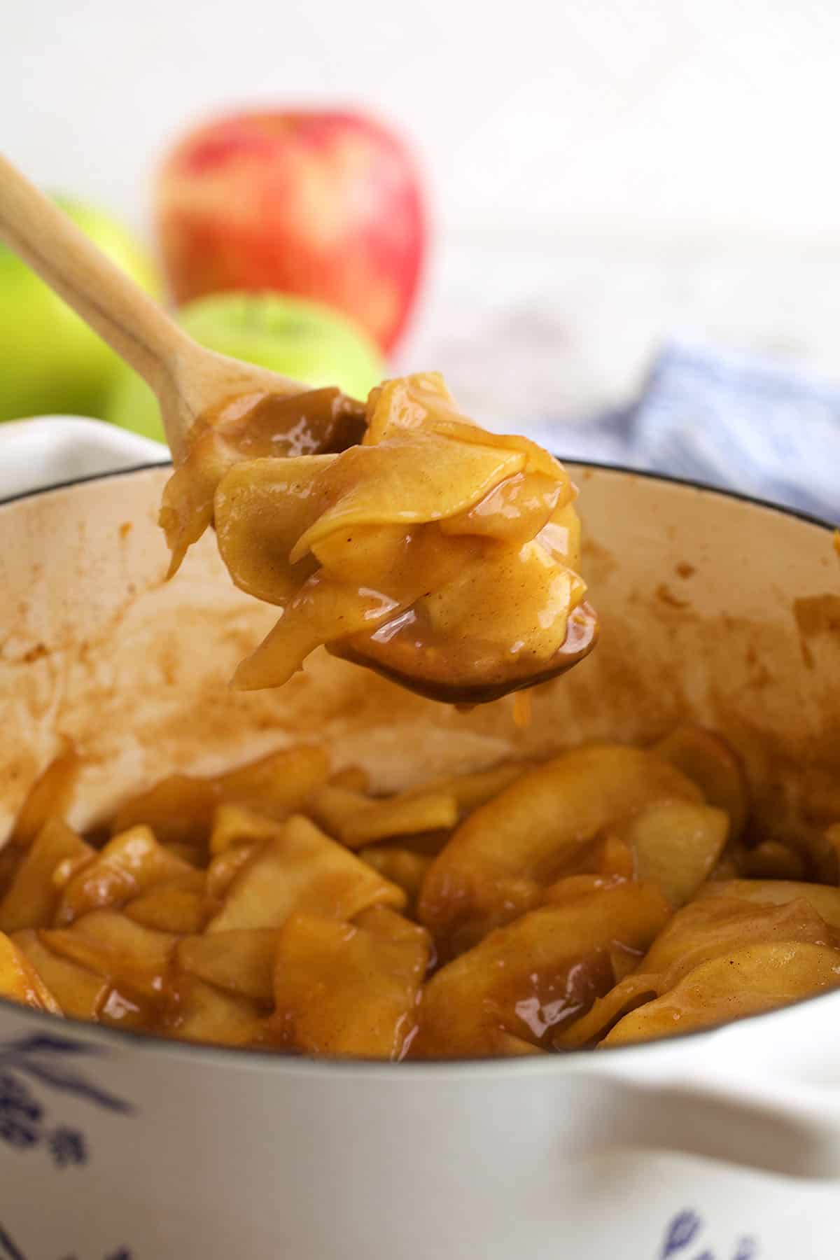 Spoonful of apple pie filling held over pot