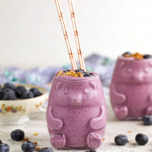 Blueberry smoothie in bear-shaped glass with glass straws