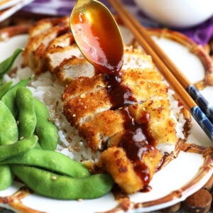 Drizzling tonkatsu sauce on plate of katsu chicken