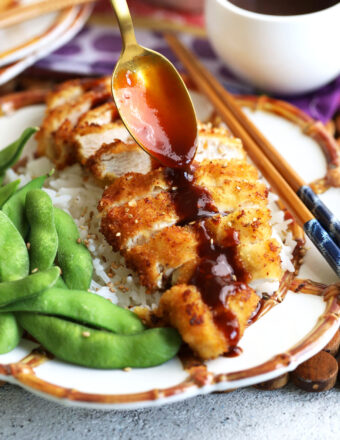 Drizzling tonkatsu sauce on plate of katsu chicken