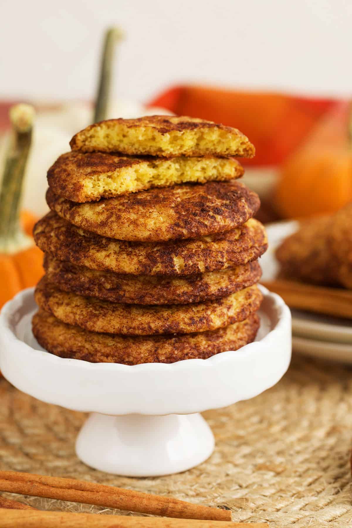 Stack of pumpkin snickerdoodles on cake stand, with one broken in half to show inside