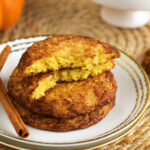 Stack of pumpkin snickerdoodles on plate, with one broken in half to show interior