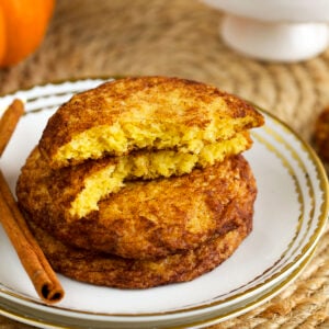 Stack of pumpkin snickerdoodles on plate, with one broken in half to show interior