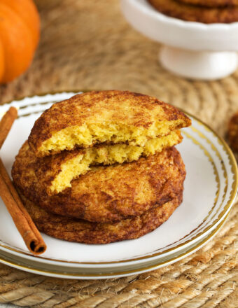 Stack of pumpkin snickerdoodles on plate, with one broken in half to show interior