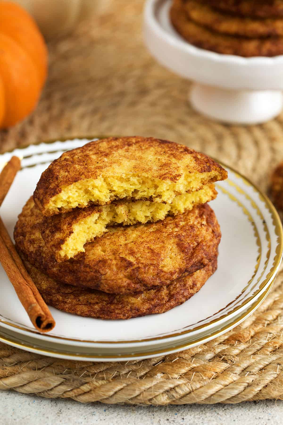 Stack of pumpkin snickerdoodles on plate, with one broken in half to show interior