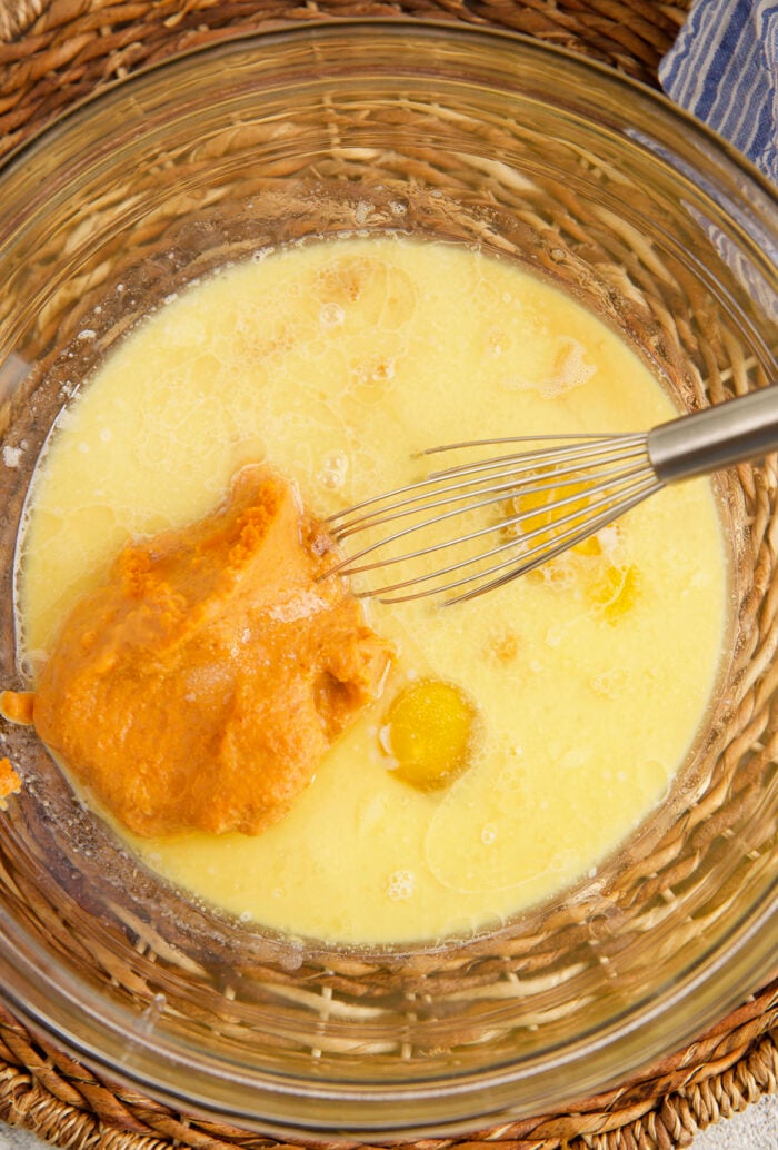 Wet ingredients for pumpkin waffles in bowl with whisk