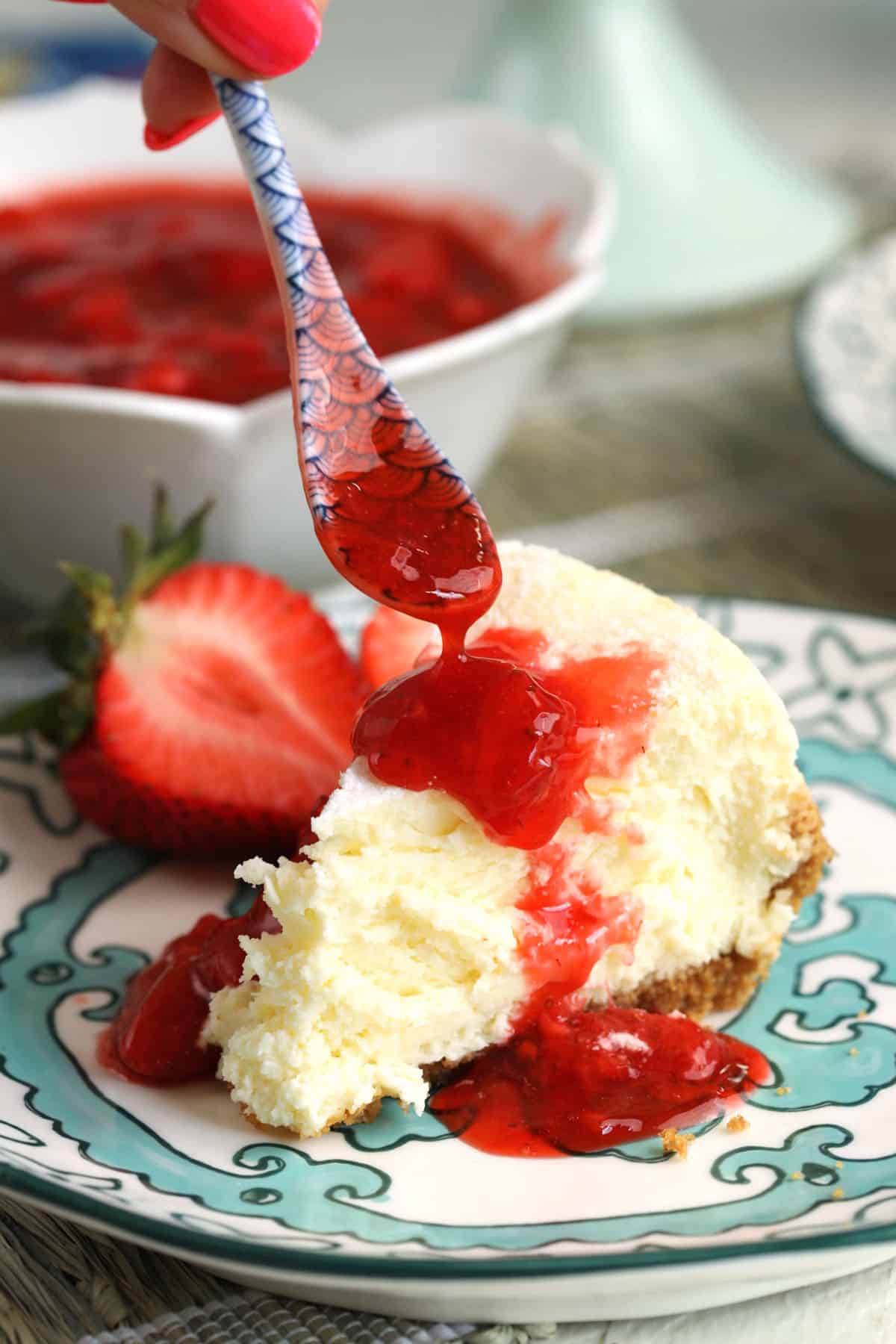 Drizzling strawberry compote over cheesecake slice