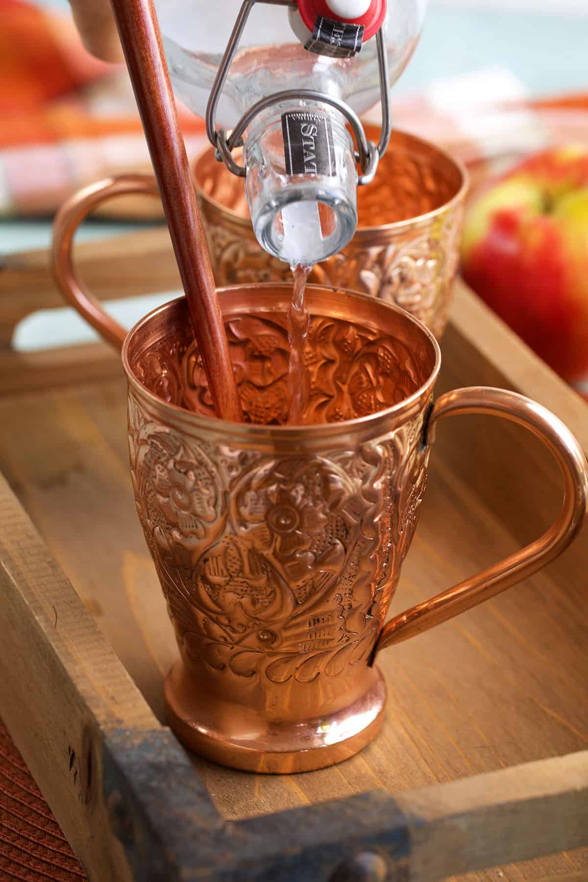 Pouring vodka into copper mug for apple cider Moscow mule