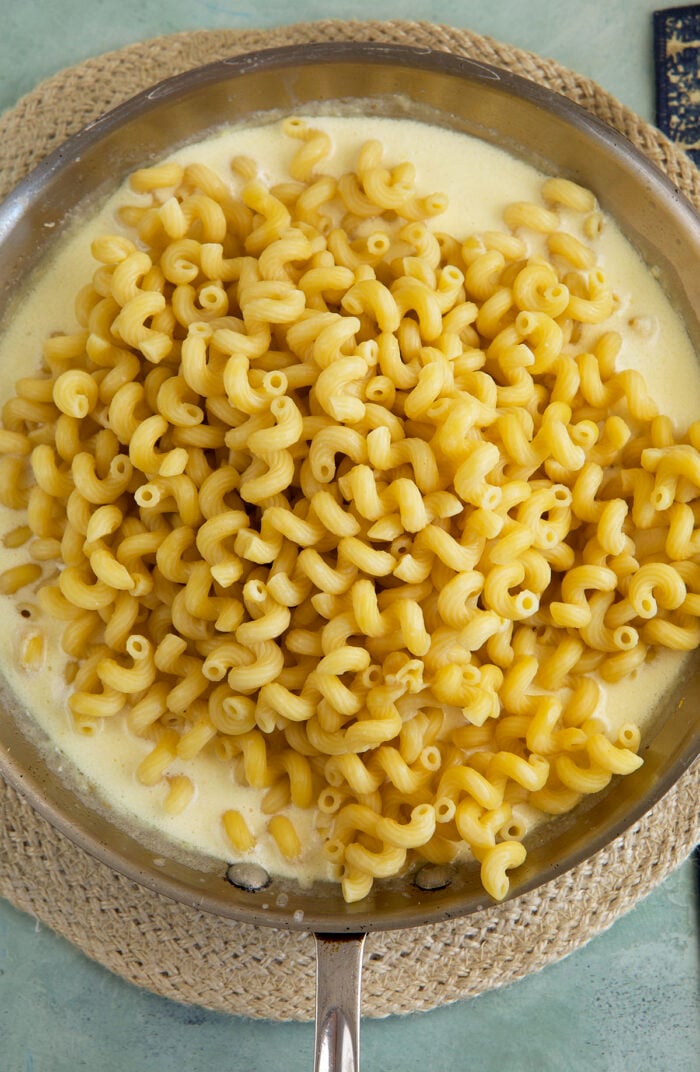 Pasta added to cream sauce in skillet