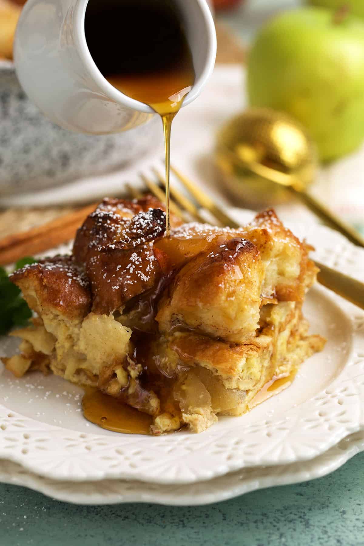 Drizzling syrup onto cinnamon apple French toast casserole on plate