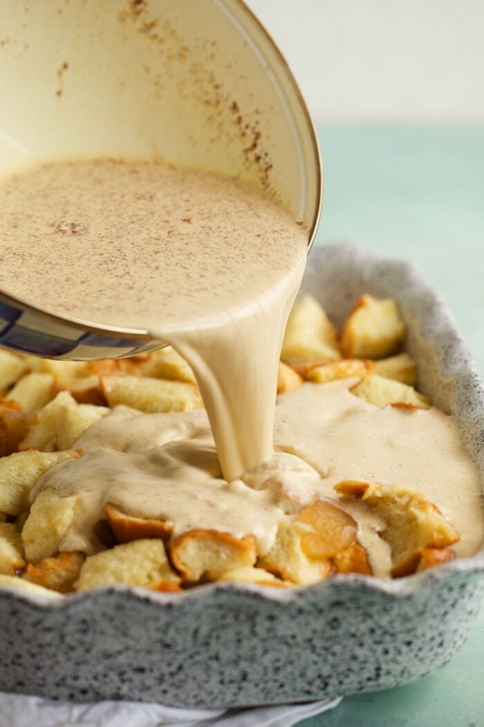 Pouring custard over bread for cinnamon apple French toast casserole