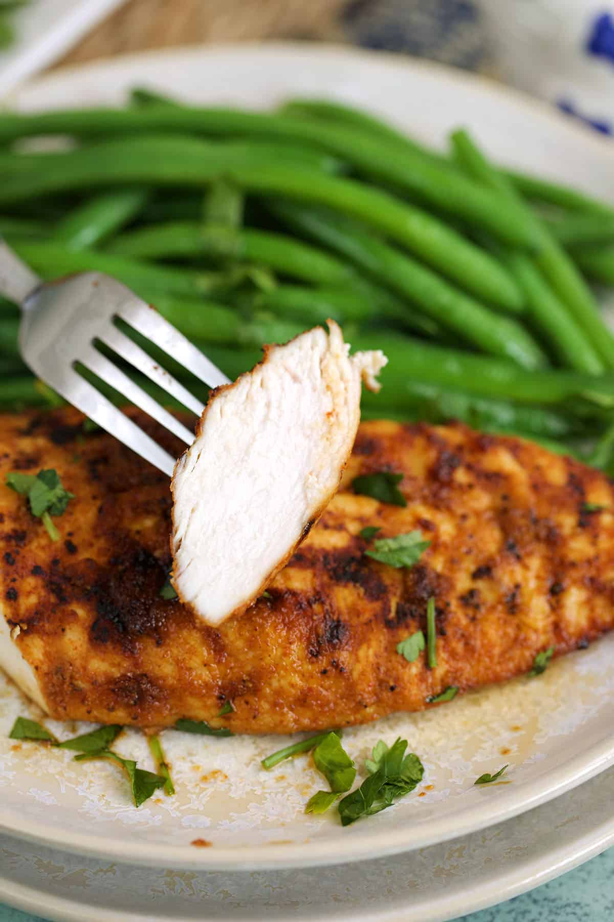 Fork picking up tender slice of air fryer chicken breast