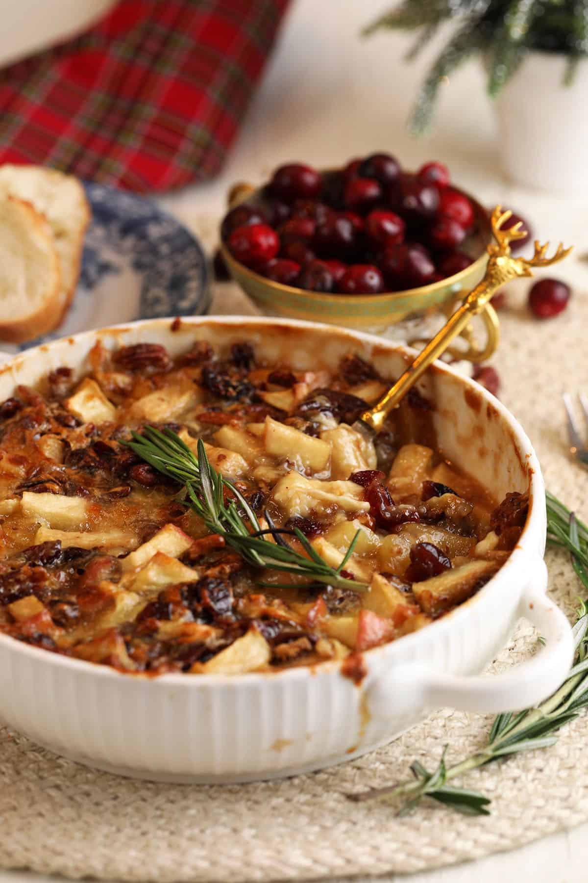 Brown sugar baked brie dip with cranberries, apples, and pecans in baking dish