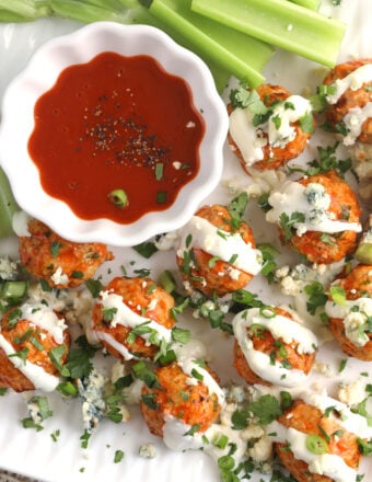 Overhead view of Buffalo chicken meatballs on serving tray with bowl of sauce