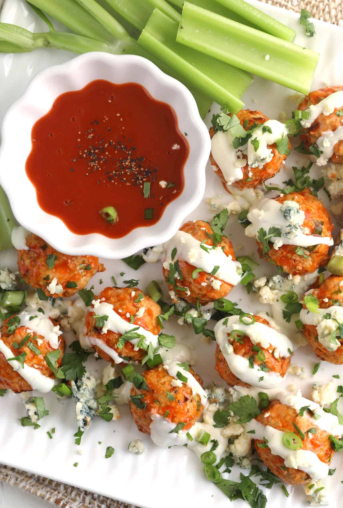 Overhead view of Buffalo chicken meatballs on serving tray with bowl of sauce