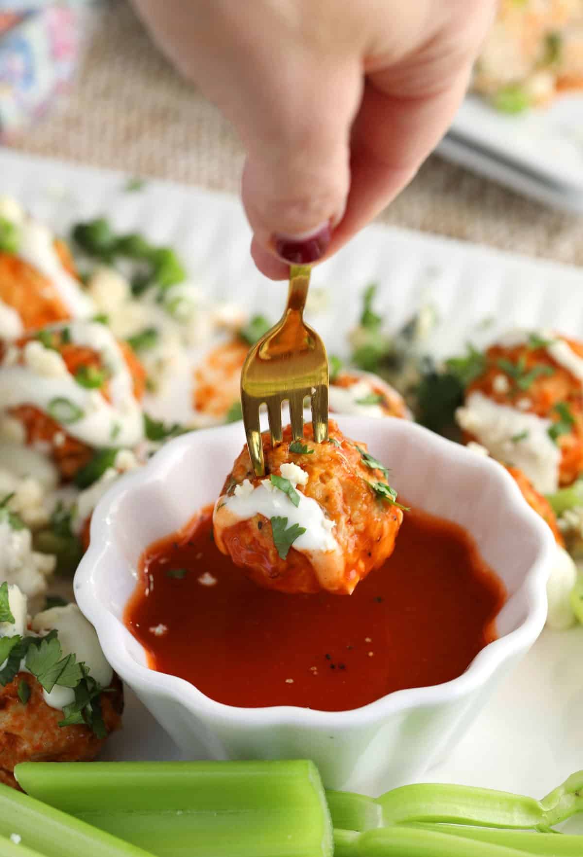 Dipping Buffalo chicken meatball in sauce