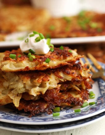 Polish potato pancakes stacked on plate with sour cream on top